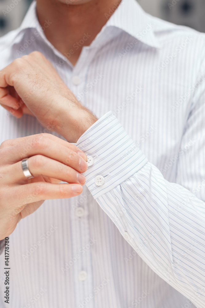 Man buttons cuff-link on French cuffs sleeves luxury white shirt. Close up of a businessman showing a shirt cuff. Man buttons cuff-link on French cuffs sleeves luxury white shirt. Close up of a businessman showing a shirt cuff.