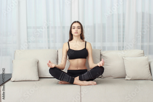 woman meditating in lotus position on the couch