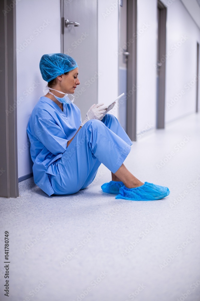 Surgeon sitting on floor and using digital tablet