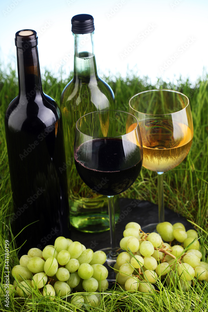 Bottle and glass of wine in fresh green gras