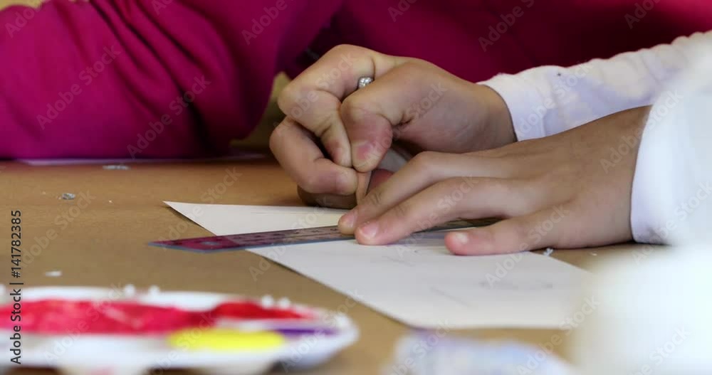 Extreme close up of a child writing large letters using a ruler Extreme close up of a child writing large letters using a ruler