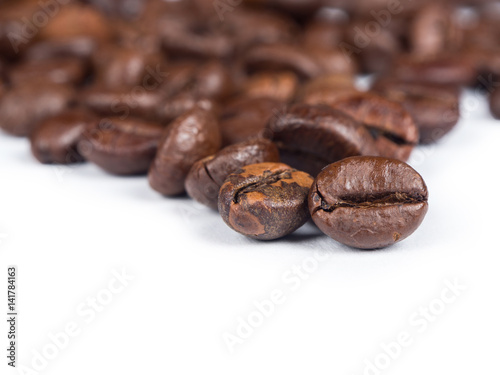 Roasted coffee grains on white isolated background from close up view