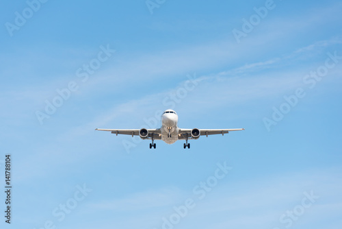 Commercial airplane flying in blue sky  full flap and landing gear extended