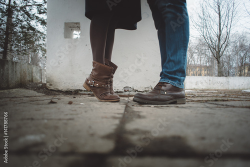 legs of a young girl with brown boots and a man in blue jeans and boots in the spring on the street close up of feet lovers