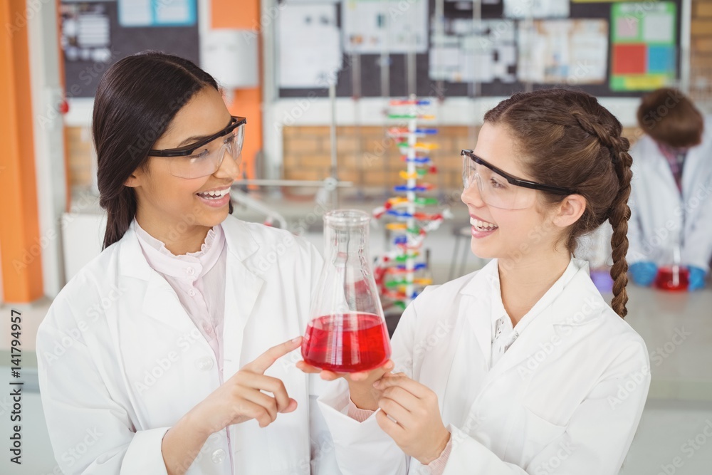 Happy schoolgirls doing a chemical experiment in laboratory Happy schoolgirls doing a chemical experiment in laboratory