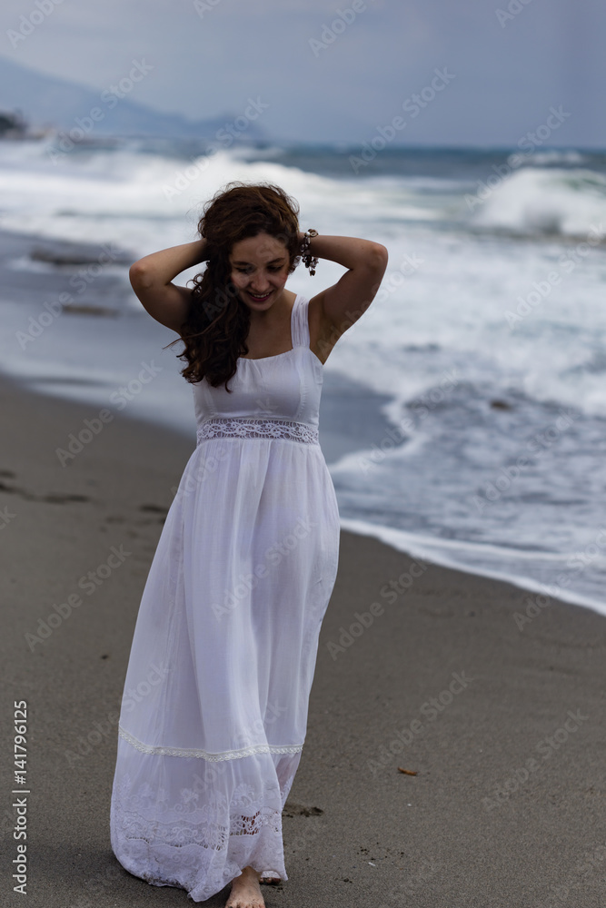 Beautiful young female walking by seaside during storm Beautiful young female walking by seaside during storm
