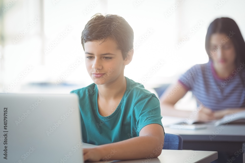 Schoolboy using laptop in classroom Schoolboy using laptop in classroom
