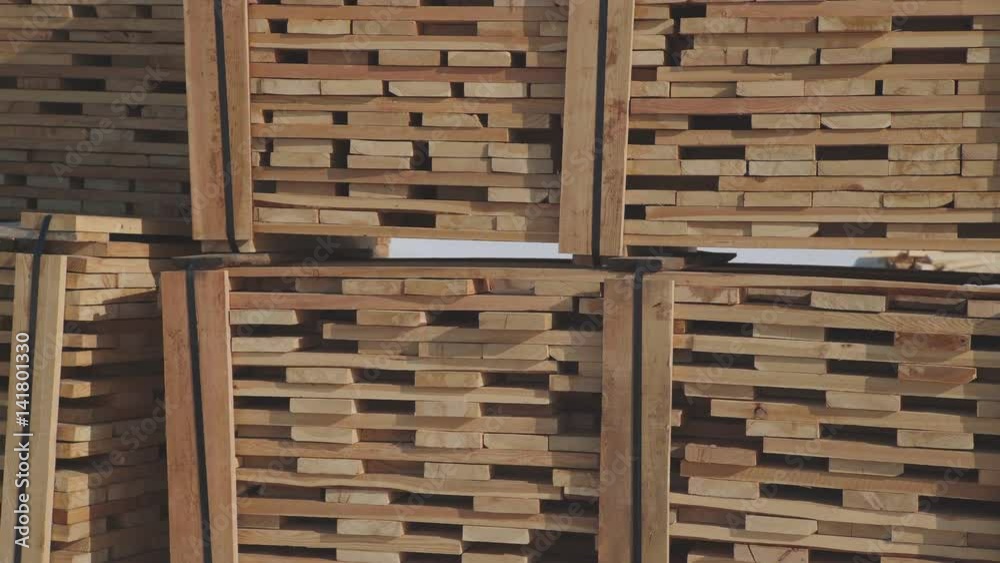Wooden blanks for the production of glued timber stand in the street in neat rows. Wooden beams and boards neatly stacked in a pyramid shape. Construction and the production of laminated veneer lumber