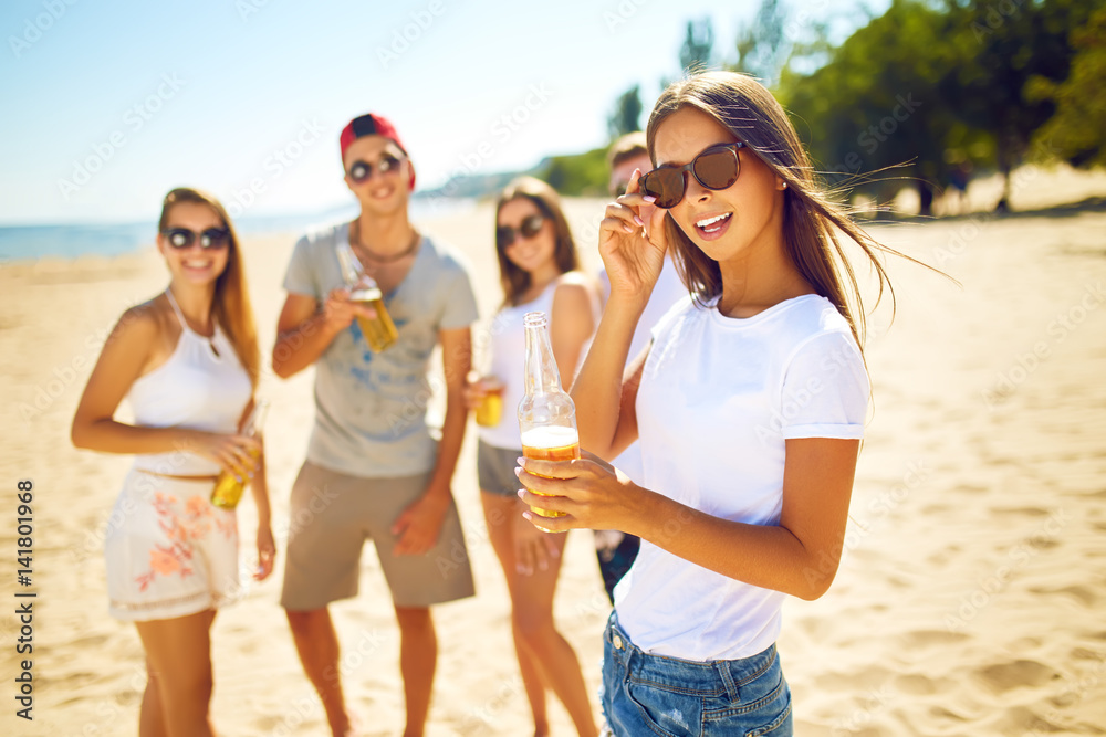 Beautiful girl with glasses is holding a bottle with beer in her hands. Group of friends hanging out with beer at the beach. Excellent sunny weather. Beautiful figures. Super mood. Summer concept
Beautiful girl with glasses is holding a bottle with beer in her hands. Group of friends hanging out with beer at the beach. Excellent sunny weather. Beautiful figures. Super mood. Summer concept