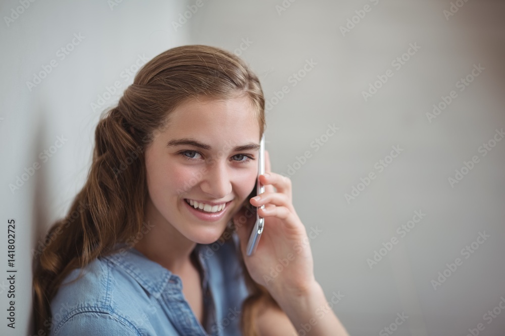 Portrait of happy schoolgirl talking on mobile phone in corridor Portrait of happy schoolgirl talking on mobile phone in corridor