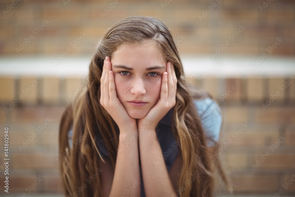 Portrait of sad schoolgirl sitting alone in campus Portrait of sad schoolgirl sitting alone in campus