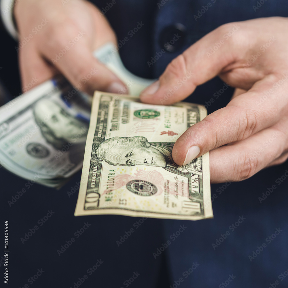 Male hand gives one ten dollars banknote, close-up view, business and finance concept. Male hand gives one ten dollars banknote, close-up view, business and finance concept.