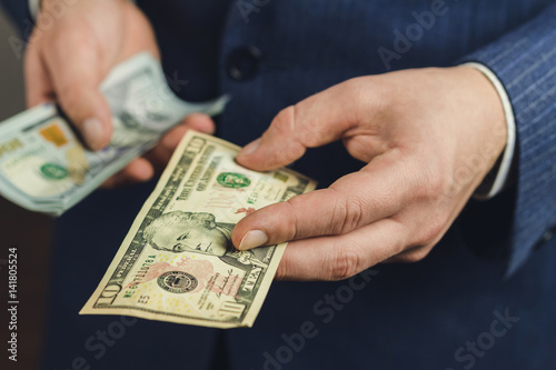 Male hand gives one ten dollars banknote, close-up view, business and finance concept.