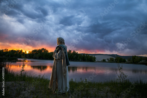 Jesus Christ next to a sun setting on the lake
