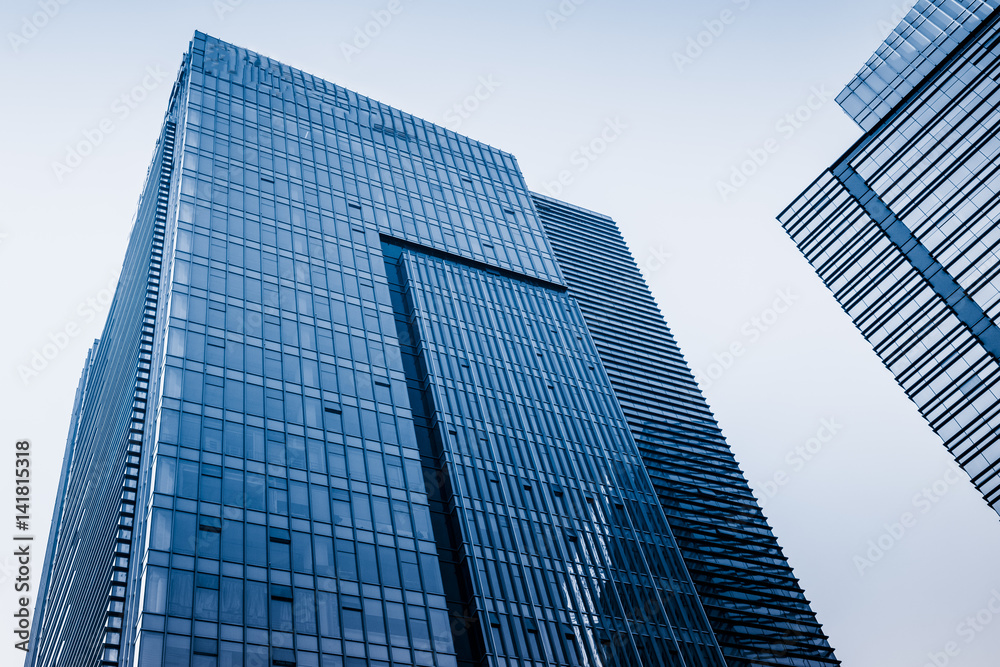 Bottom view of modern skyscrapers in business district against blue sky Bottom view of modern skyscrapers in business district against blue sky