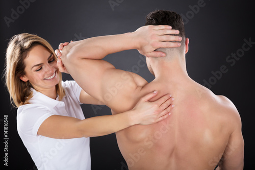 Smiling Female Physiotherapist Giving Shoulder Massage
