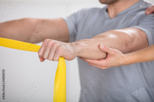 Physiotherapist Giving Man A Training With Exercise Band