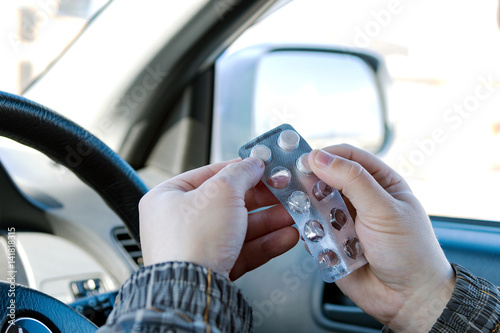 Driver driving his car drinks tablets from disease