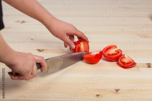 Cutting tomatoes for dishes on the table. Vegetables during the cooking process dishes. Vegetables for healthy eating and dieting photo