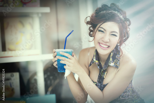Beautiful young woman in cafe drinking blue soda ice and relaxing on a summer day