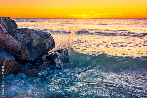 Waves crashing on the rocks at sunset