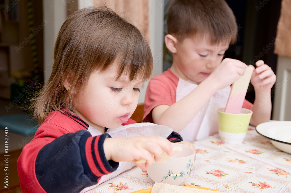 Fototapeta premium children eating lunch at home healthy food concept kids enjoying bread and yogurt sibling emotional faces healthy breakfast for brother and sister
