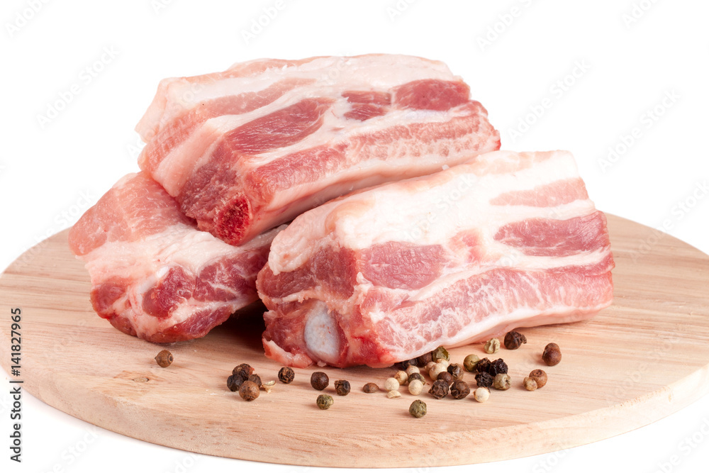 pieces of pork with peppercorn on a cutting board isolated on white background