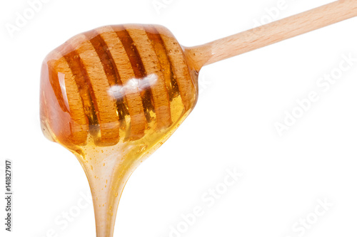 Honey flowing from wooden stick isolated on white background