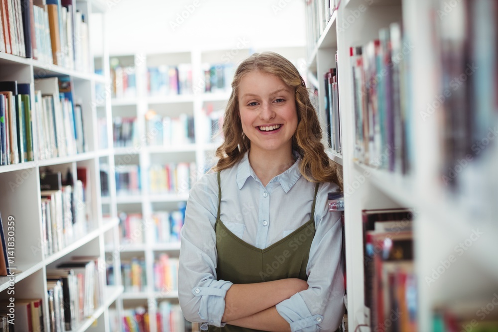 Portrait of schoolgirl standing with arms crossed in library Portrait of schoolgirl standing with arms crossed in library