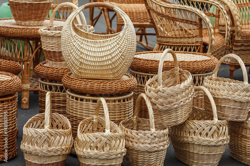 A variety of braided vines items are on the ground. Baskets are in the foreground. Wicker chairs and tables at a village fair. Traditional Belarusian Handicrafts. photo