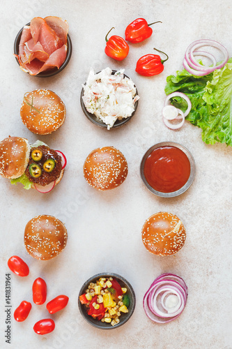 Mini party burgers with a dip and various fillings on rustic surface. Top view, blank space
