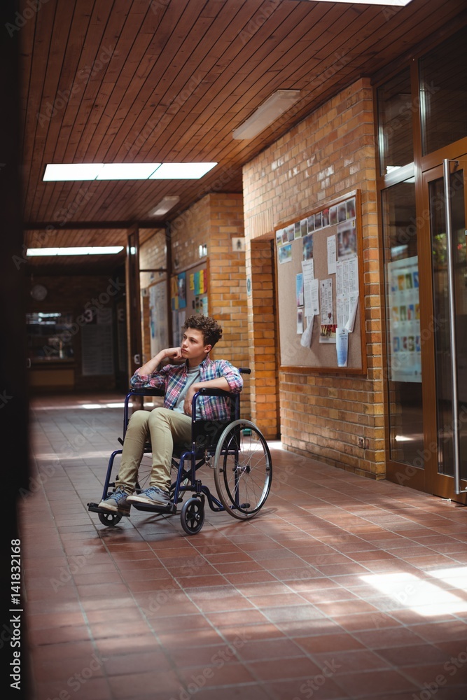 Obraz premium Disabled schoolboy on wheelchair in corridor at school