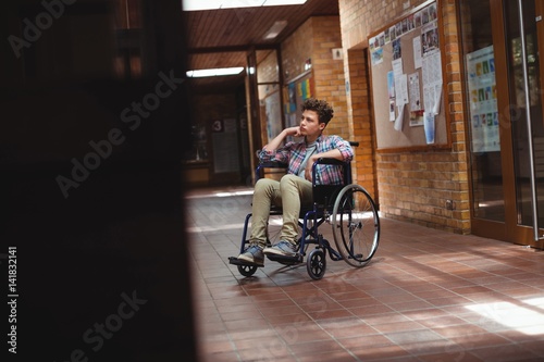 Disabled schoolboy on wheelchair in corridor at school