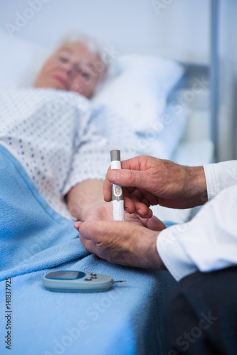 Doctor testing diabetes of senior patient with insulin pen