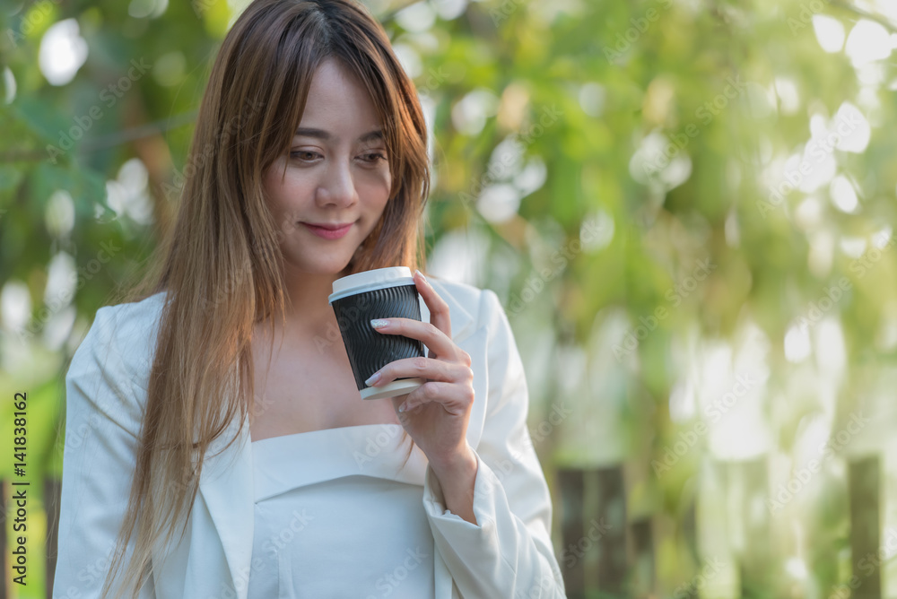Beautiful woman holding a cup of coffee enjoying and happy the smell of her hot coffee, anticipating the sweet taste on natural light in the morning. Beautiful woman holding a cup of coffee enjoying and happy the smell of her hot coffee, anticipating the sweet taste on natural light in the morning.
