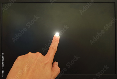  human finger touching on black computer screen and light on 