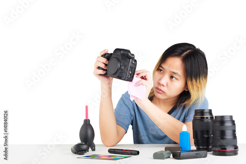 Asian woman cleaning a camera with cloth and photography equipment on table. object isolated on white background with clipping path and copy space.