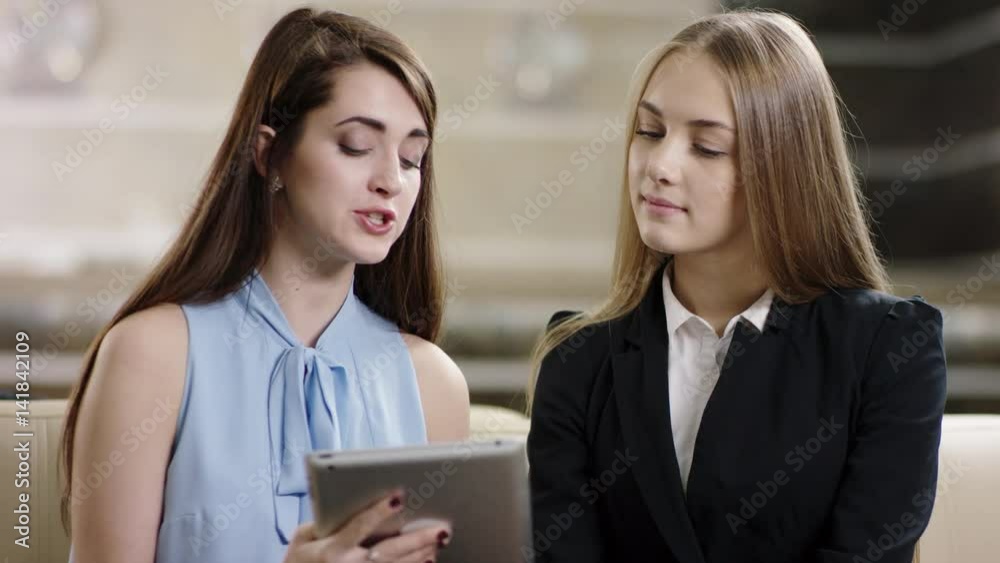 businesswomen discussing work and using devise businesswomen discussing work and using devise