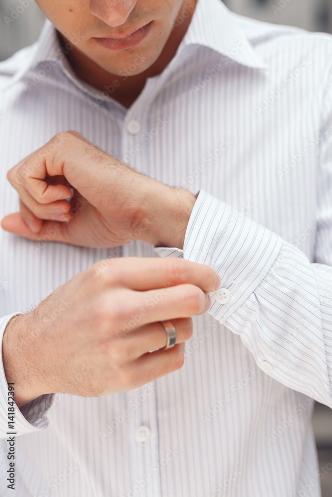 Obraz premium Close up of a hand businessman how wears white shirt and cufflink. Elegant white shirt with buttons.