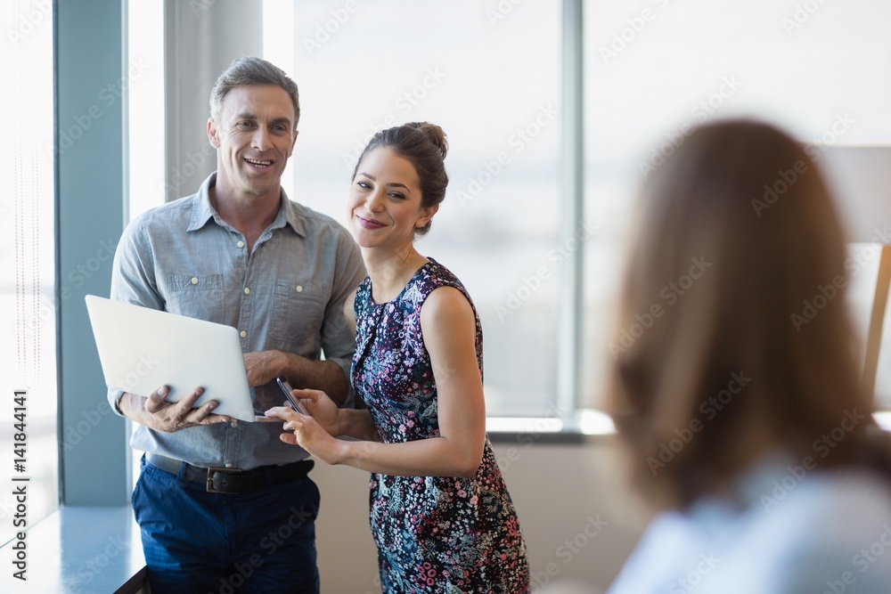 Fototapeta premium Smiling business colleagues discussing over laptop