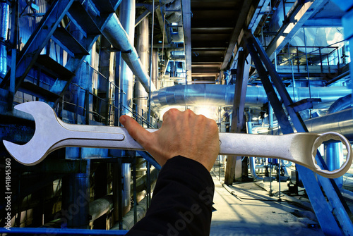 Service Factory concept background. Hand holding a wrench against factory photo photo