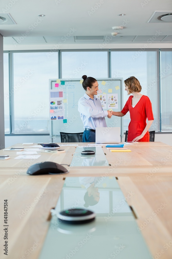 Obraz premium Smiling business colleagues shaking hands in conference room
