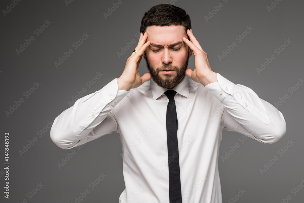 Portrait of young handsome man in gray jacket and white shirt with hands on temples suffering from headache Portrait of young handsome man in gray jacket and white shirt with hands on temples suffering from headache