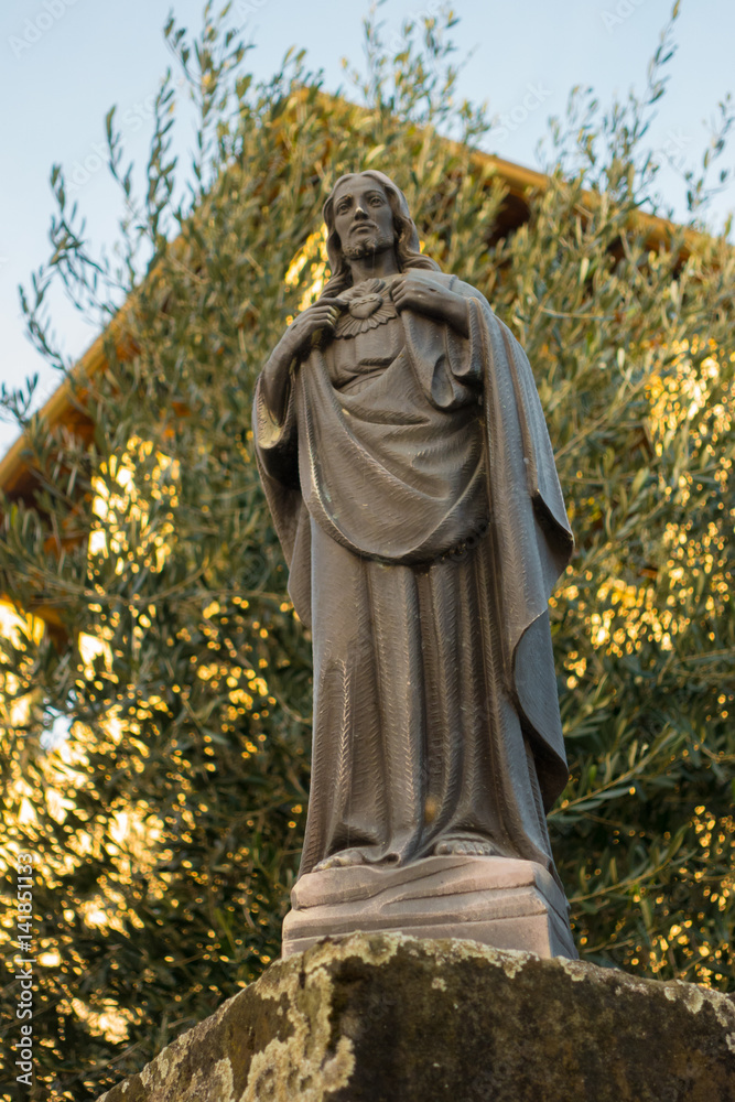 Jesus Christ statue with olive tree in the background