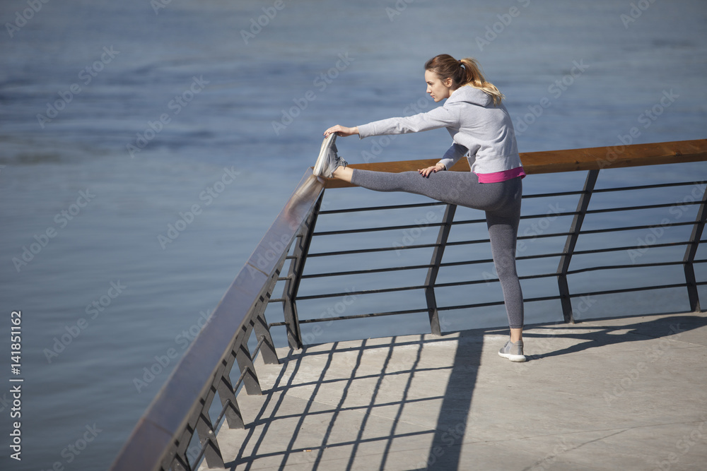 Morning exercise along the river. A young woman on recreation and jogging