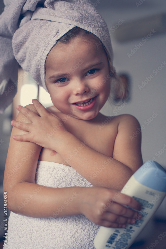 Little girl putting lotion on her skin. Stock Photo Adobe Stock
