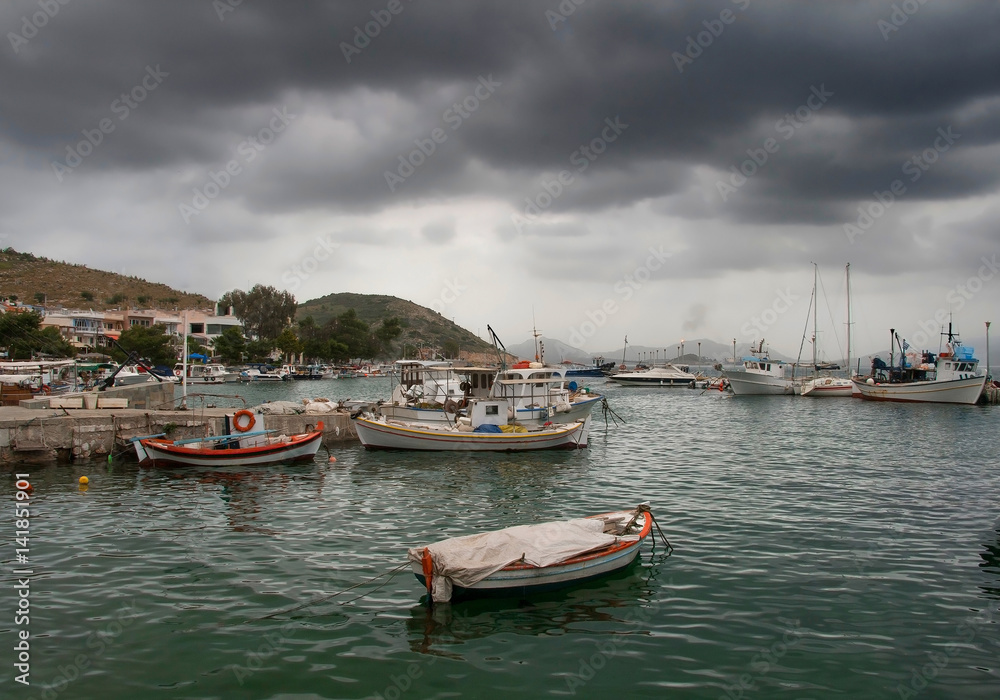 Fishing boats in small harbour under a rainy cloudscape