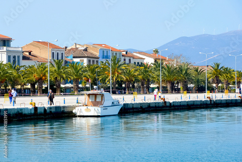 View of small touristic and historical city (Nafplion,1st capital of Greece) with traditional houses, palm trees and people walking on a sunny day