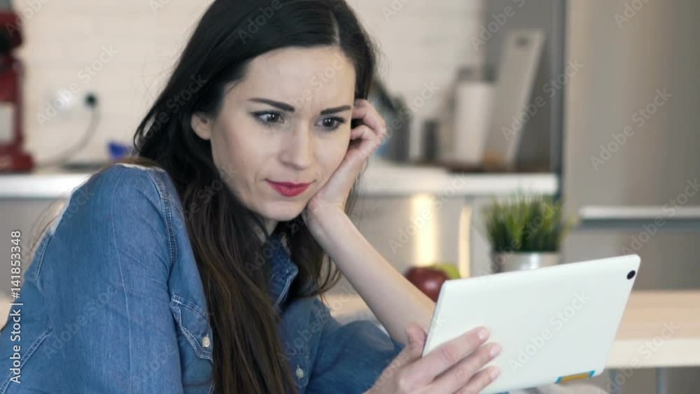 Pretty, young woman watching movie on tablet computer sitting on sofa
