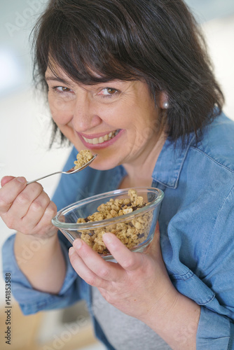 Dark-haired woman in kitchen eating cereals